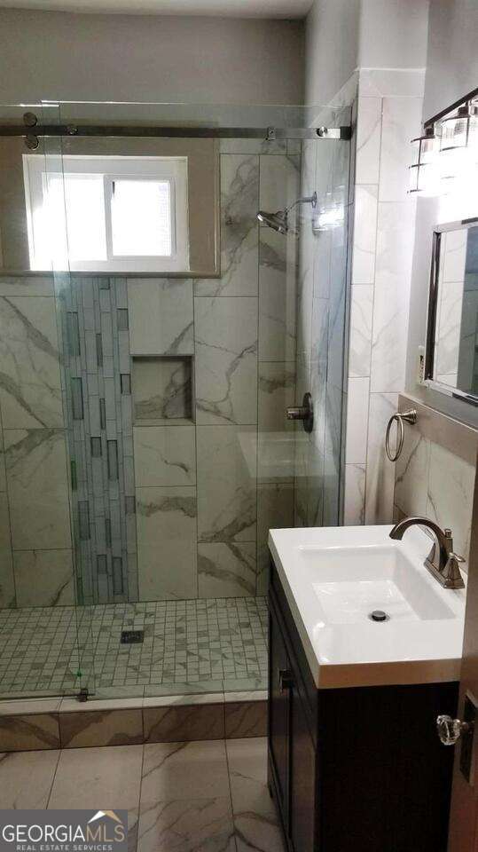 full bathroom featuring vanity, a shower stall, and marble finish floor