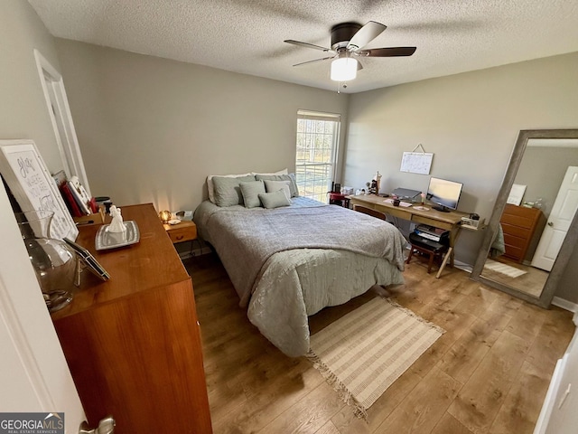 bedroom with a textured ceiling, ceiling fan, and light wood finished floors