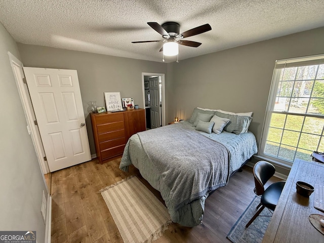 bedroom with baseboards, a textured ceiling, ceiling fan, and wood finished floors