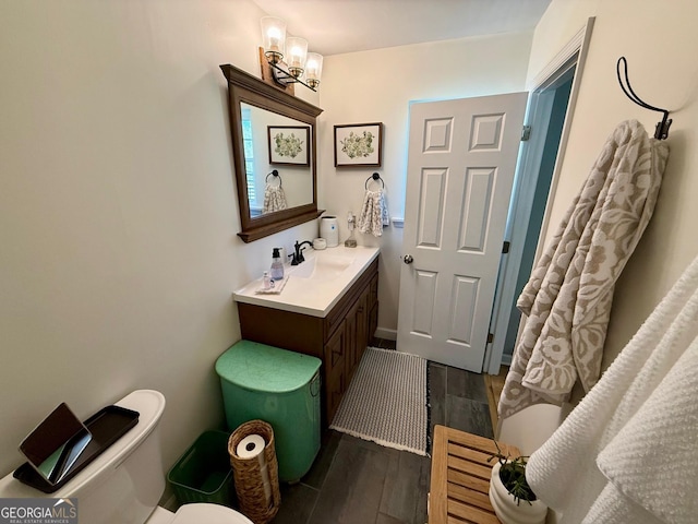 bathroom with toilet, vanity, and wood finished floors