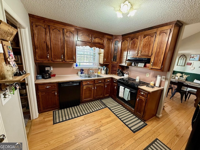 kitchen with a sink, black appliances, exhaust hood, and light wood finished floors