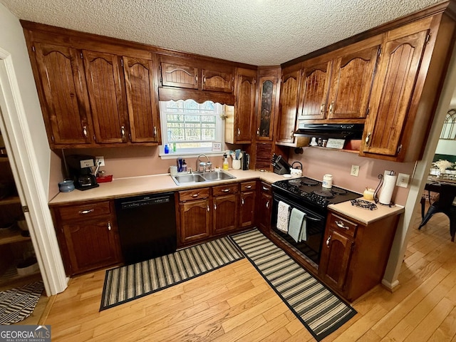 kitchen with black appliances, light countertops, light wood finished floors, and a sink