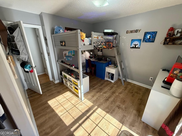 interior space featuring a textured ceiling, baseboards, and wood finished floors