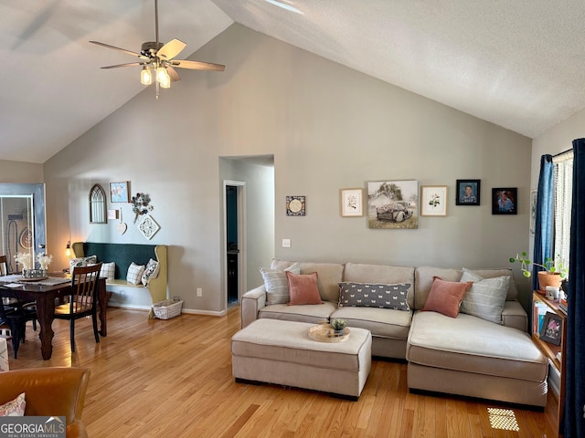 living area with high vaulted ceiling, light wood-style floors, baseboards, and ceiling fan