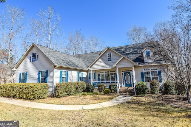 view of front facade with a porch, a shingled roof, and a front lawn