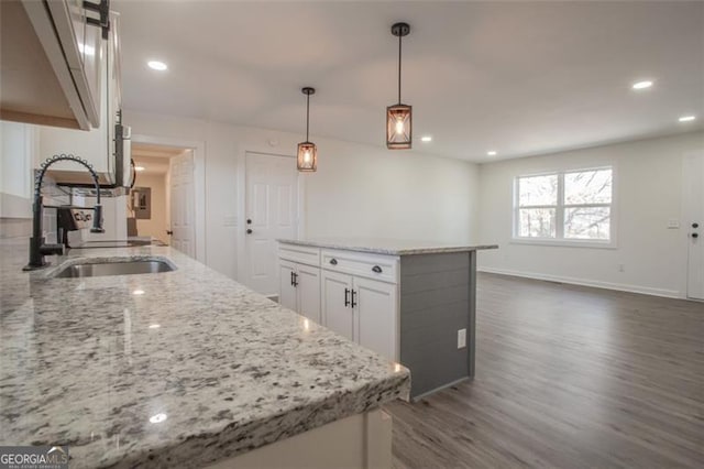 kitchen featuring dark wood-type flooring, light stone counters, recessed lighting, white cabinets, and a sink