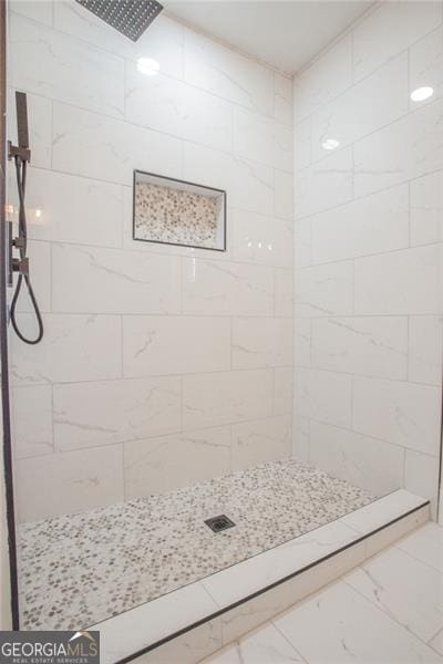 full bath with marble finish floor and tiled shower