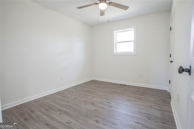 empty room with baseboards, wood finished floors, and a ceiling fan