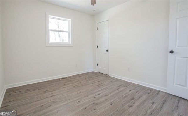 empty room featuring visible vents, ceiling fan, baseboards, and wood finished floors