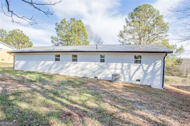 rear view of property featuring cooling unit, brick siding, a yard, and crawl space