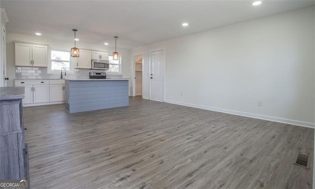 kitchen featuring stainless steel microwave, wood finished floors, open floor plan, and a sink