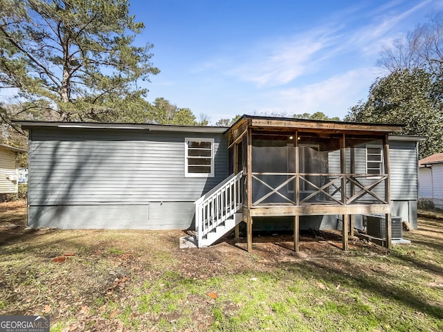 rear view of house with central AC and a sunroom