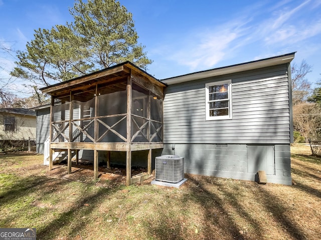 rear view of property featuring a lawn, cooling unit, and a sunroom