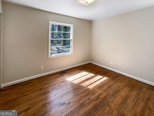 spare room featuring visible vents, baseboards, and wood finished floors