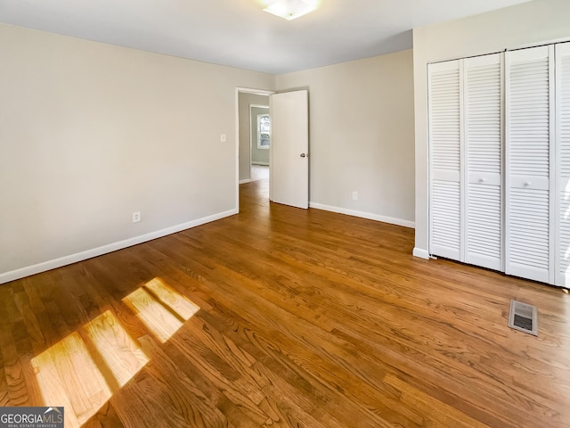 unfurnished bedroom featuring visible vents, baseboards, and wood finished floors