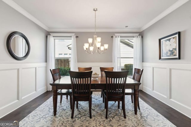 dining space with a healthy amount of sunlight, a chandelier, and wainscoting