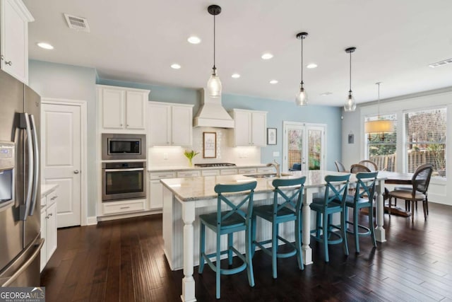 kitchen featuring custom exhaust hood, visible vents, appliances with stainless steel finishes, and a sink