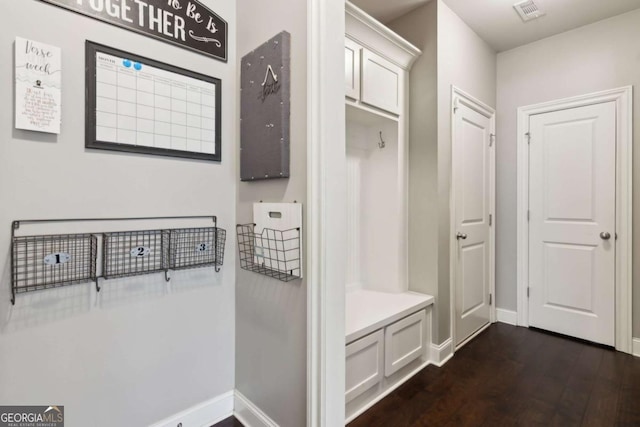 mudroom with dark wood finished floors, baseboards, and visible vents