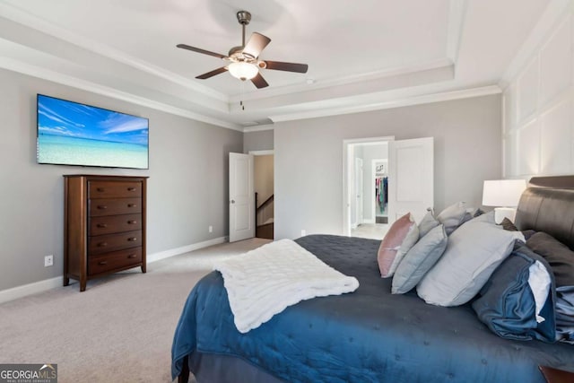 bedroom with a tray ceiling, crown molding, light colored carpet, and baseboards