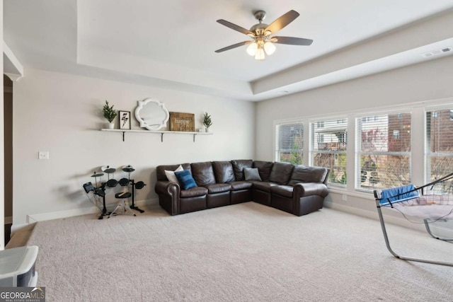 carpeted living room featuring a raised ceiling, baseboards, visible vents, and ceiling fan