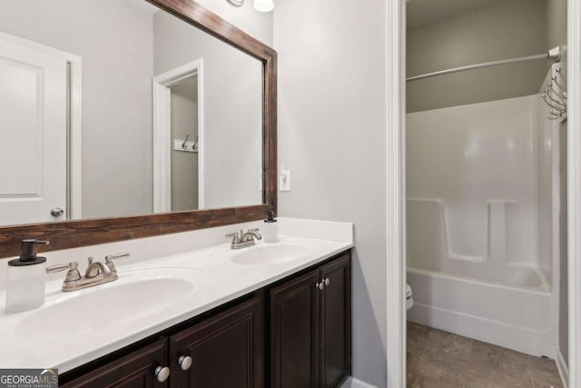 full bathroom featuring double vanity, toilet, tile patterned floors, and a sink