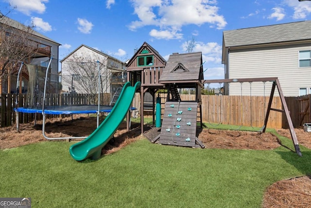 view of jungle gym with a lawn, a fenced backyard, and a trampoline