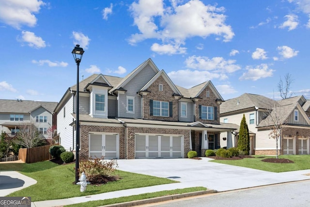 view of front facade featuring a front yard, fence, driveway, an attached garage, and brick siding