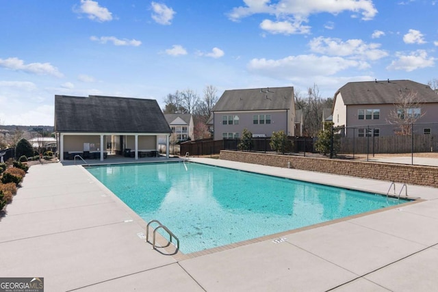 pool featuring a residential view, an outbuilding, fence, and a patio area