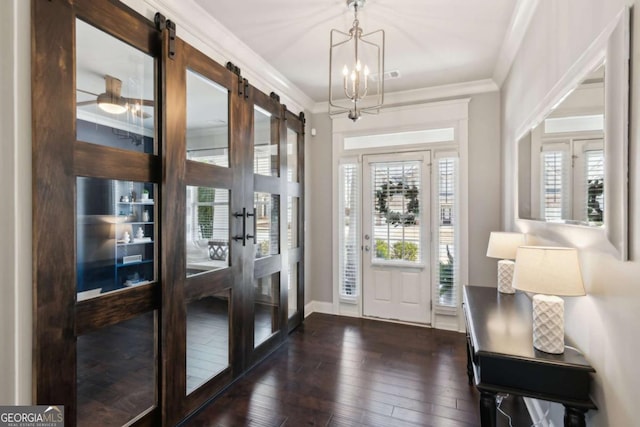 entryway with visible vents, ornamental molding, dark wood finished floors, a barn door, and a chandelier