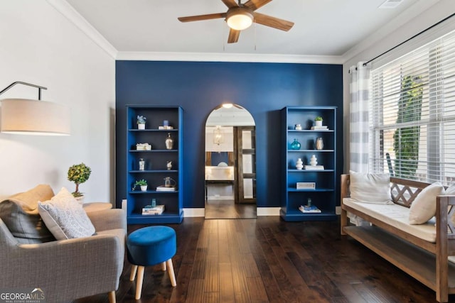 living area with arched walkways, hardwood / wood-style flooring, a ceiling fan, and ornamental molding