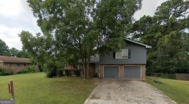 split level home with a front lawn, concrete driveway, and a garage