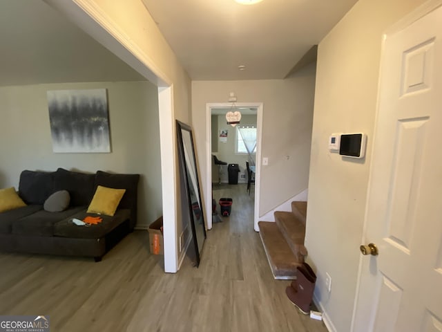 hall featuring stairs, light wood-type flooring, and baseboards