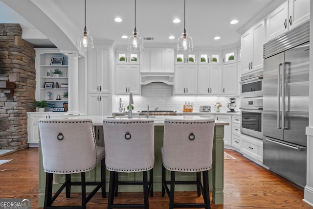 kitchen with stainless steel appliances, light countertops, custom range hood, and wood finished floors