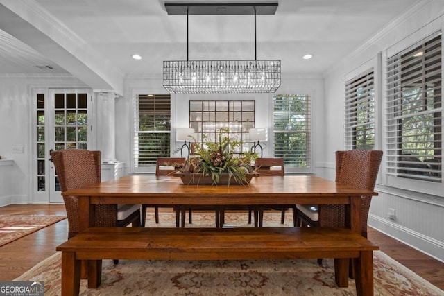 dining space featuring wood finished floors, ornate columns, recessed lighting, ornamental molding, and a notable chandelier