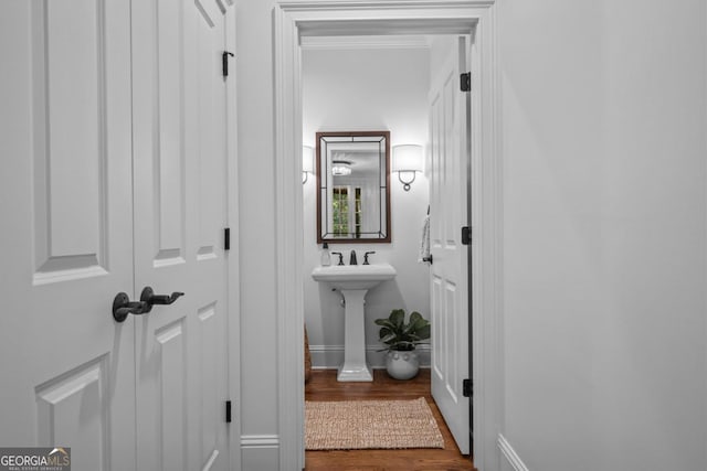 bathroom featuring crown molding, wood finished floors, baseboards, and a sink