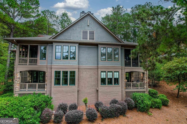 exterior space featuring a chimney, a sunroom, and stucco siding