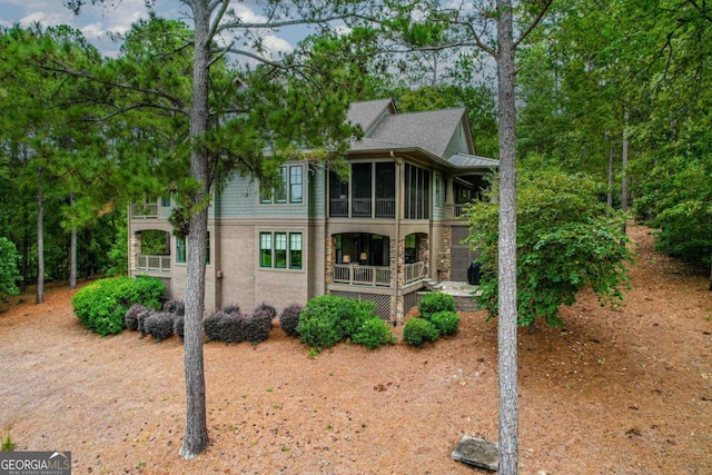 view of front of house with stucco siding, a balcony, and a sunroom