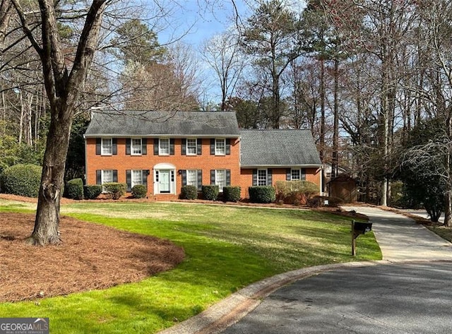 colonial home with a front lawn and brick siding