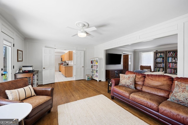 living room featuring ceiling fan, light wood-style floors, and ornamental molding