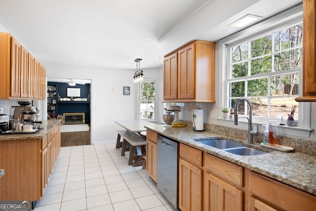 kitchen with tasteful backsplash, dishwasher, light stone counters, light tile patterned flooring, and a sink