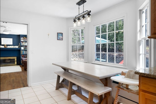 dining space with light tile patterned floors, baseboards, breakfast area, and a glass covered fireplace