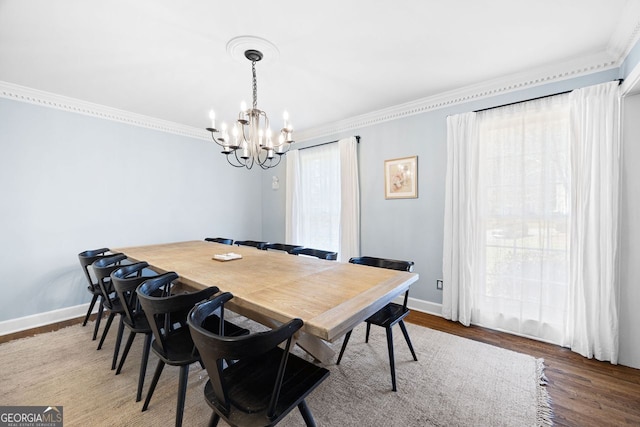 dining space featuring baseboards, an inviting chandelier, wood finished floors, and crown molding