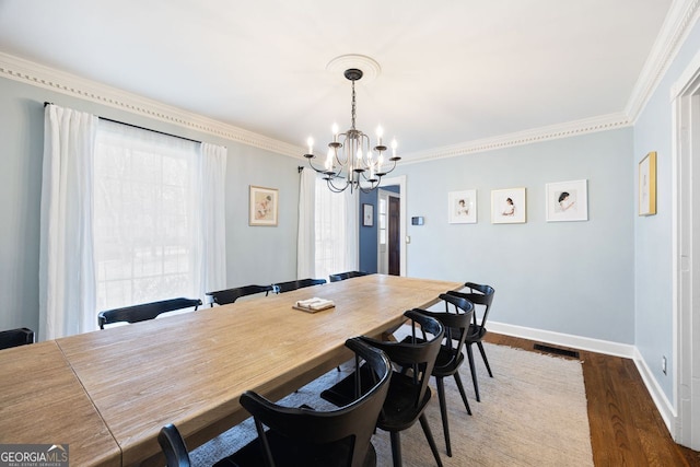 dining space featuring baseboards, dark wood-type flooring, a chandelier, and ornamental molding