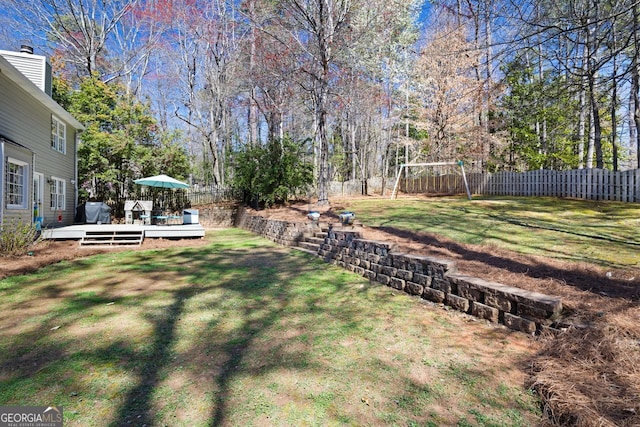 view of yard featuring a playground, a fenced backyard, and a wooden deck