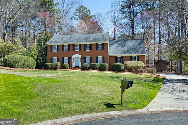 colonial inspired home featuring a front yard, concrete driveway, and brick siding