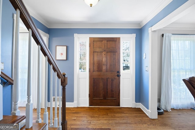 foyer entrance with stairway, crown molding, and wood finished floors