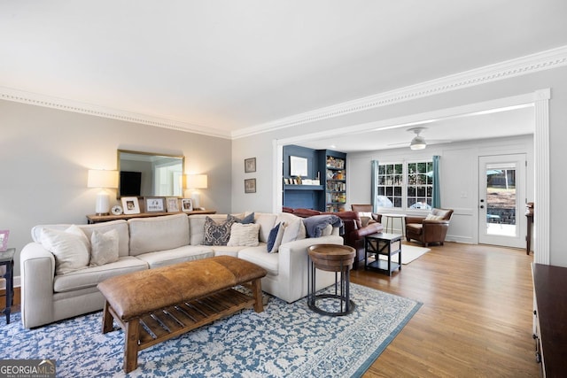 living room with ceiling fan, wood finished floors, and ornamental molding