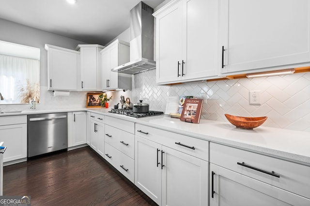 kitchen featuring white cabinets, wall chimney exhaust hood, decorative backsplash, and stainless steel appliances