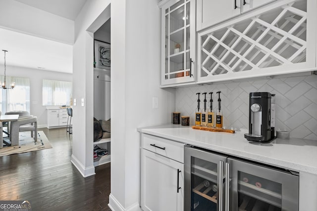 bar with baseboards, beverage cooler, a dry bar, decorative backsplash, and dark wood-style floors