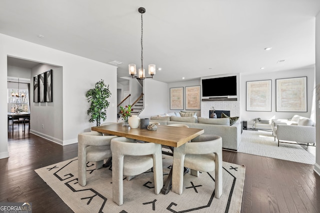 dining area featuring dark wood-style floors, stairway, baseboards, and an inviting chandelier